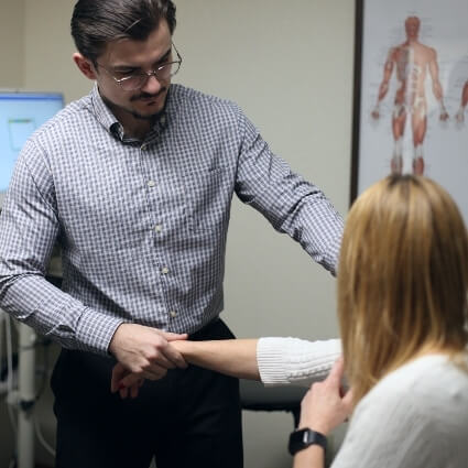 Dr. Markokaj assessing a patient's arm